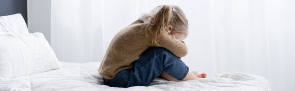 side view of upset girl obscuring face while sitting on bed, banner - Photo, Image