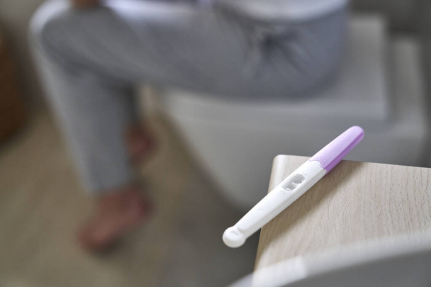 Detail of pregnancy test and defocused woman in the background  - Foto, immagini