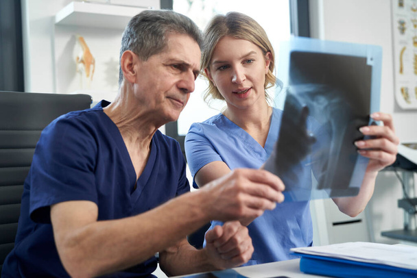 Два кавказских врача обсуждают рентгеновское изображение - Фото, изображение