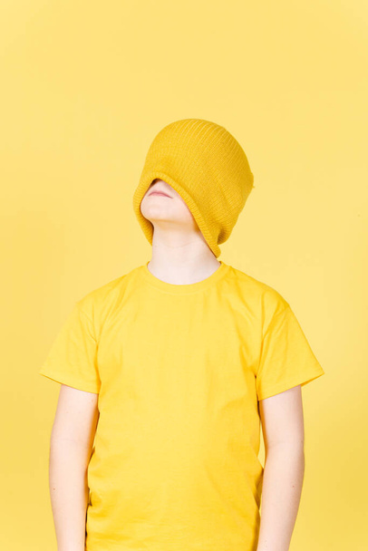 Niño con los ojos vendados soñando y mirando hacia arriba sobre fondo amarillo. Concepto de niño confuso - Foto, Imagen