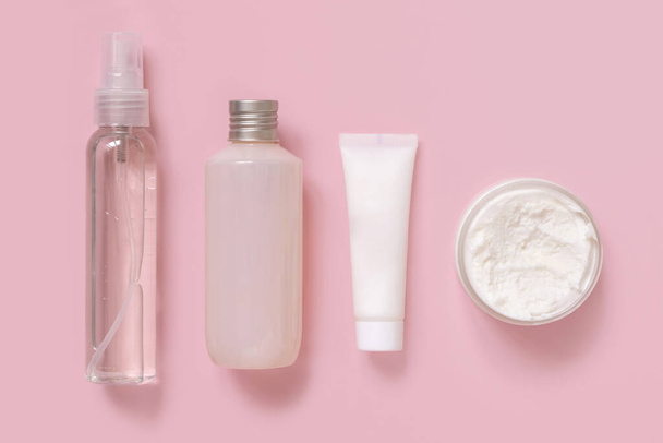 Házi készítésű kozmetikumok műanyag csövekben és üvegekben rózsaszín felülnézetben. Márkás csomagolás mockup. Természetes szerves kozmetikumok bőr- és hajápoláshoz - Fotó, kép