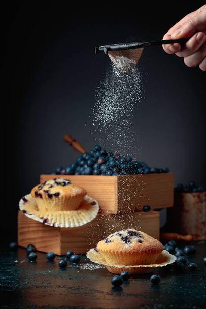 Muffin ai mirtilli e bacche in una scatola di legno. Muffin cosparsi di zucchero in polvere. Pasticcini pasquali. - Foto, immagini