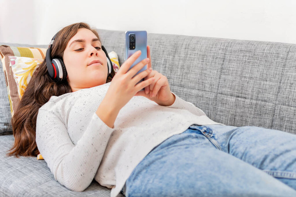 happy woman listening to music on sofa at home - 写真・画像