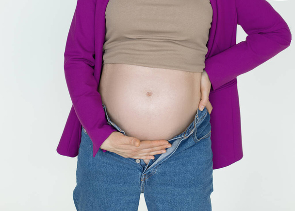 Terhes has fehér háttér, felismerhetetlen nők támogatják a kezét terhes has, fájdalom a terhesség alatt  - Fotó, kép