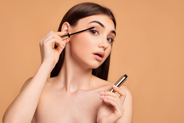 woman hold mascara isolated on beige background - Foto, immagini