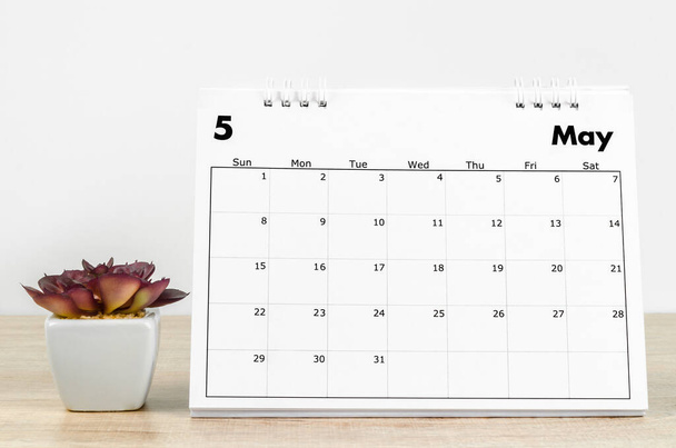 The May 2022 desk calendar with plant pot on wooden table. - Foto, Imagen