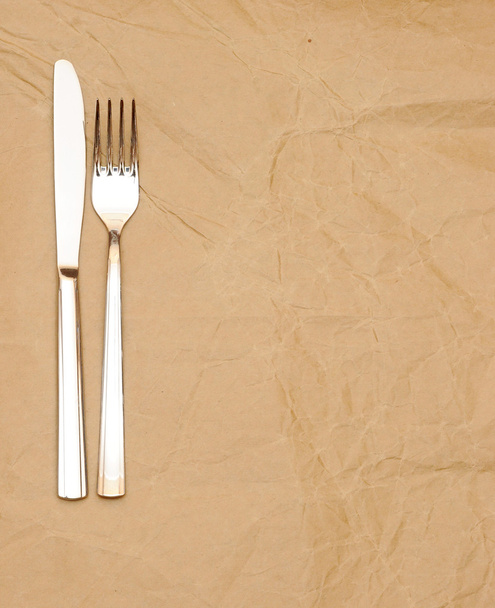 Cuchillo y tenedor sobre papel viejo. espacio para el texto
 - Foto, Imagen