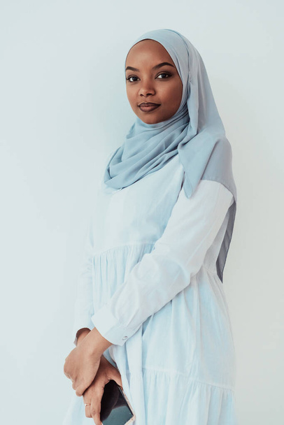 An African Muslim woman using a smartphone on a white background - 写真・画像