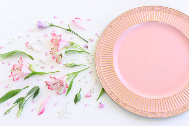 Top view of vintage white empty plate over spring flowers. Flat lay - Foto, imagen