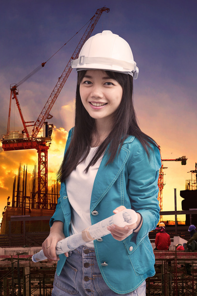 Vrouwelijke ingenieur met bouwmaterieel tegen het bouwen van stuctur - Foto, afbeelding