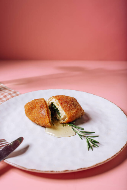 A classic dish of Ukrainian is a Kiev cutlet on a white plate on a pink background. High quality photo - 写真・画像
