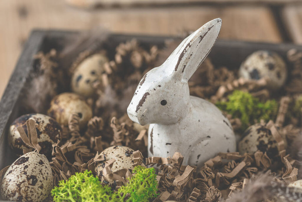 Décoration en bois lapin de Pâques avec petits œufs de caille et décoration aux couleurs naturelles, tradition chrétienne - Photo, image