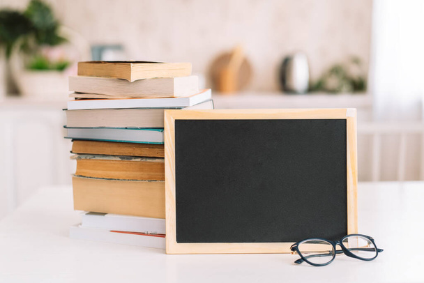 Stack of books with glasses and chalkboard standing on table - Photo, Image
