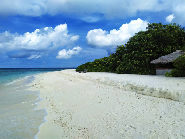 Maldives, the empty beach with small water cafe. A white sand, turquoise ocean and a blue sky. - Photo, Image