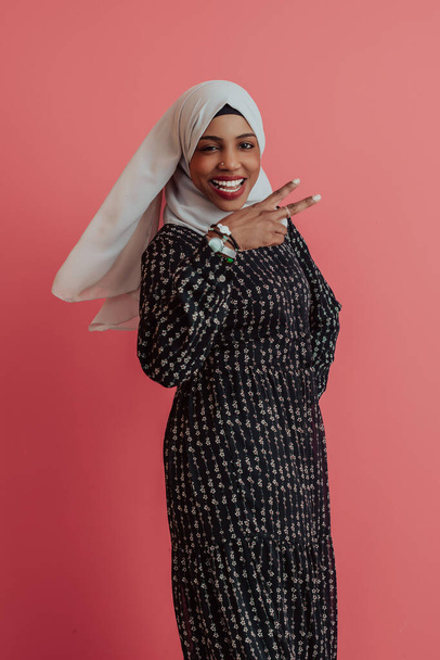 Portrait of young modern muslim afro beauty wearing traditional islamic clothes on plastic pink background. Selective focus  - Foto, afbeelding