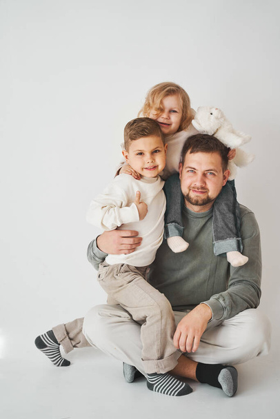 Happy family. Father, daughter and son hugging and smiling on white background. Paternity. Single father bring up his children - Photo, image