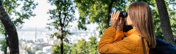 Side view of young woman looking through binoculars near boyfriend outdoors, banner   - Valokuva, kuva