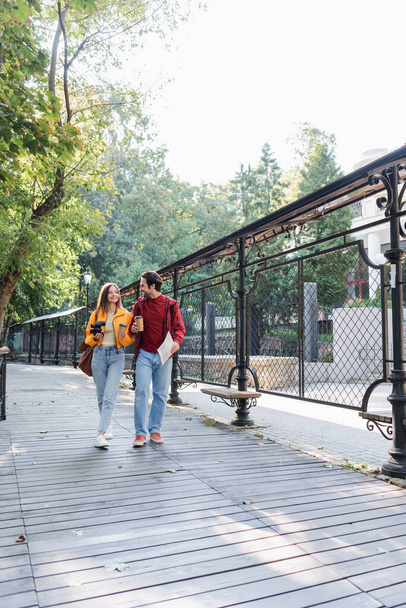 Веселые путешественники с биноклем, бумажные стаканчики и карта ходьбы по городской улице  - Фото, изображение