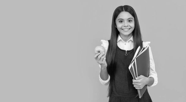 Happy školní dítě úsměv drží jablko a knihy oranžové pozadí kopírovat prostor, školní - Fotografie, Obrázek