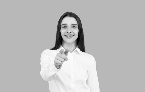χαμογελαστή επιχειρηματίας γυναίκα σε λευκό πουκάμισο δείχνοντας δάχτυλο σε γκρι φόντο, CEO - Φωτογραφία, εικόνα