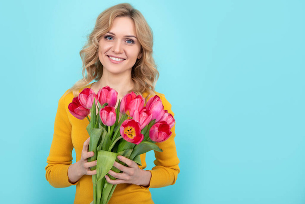 mosolygós lány tavaszi tulipán virágok kék háttér - Fotó, kép