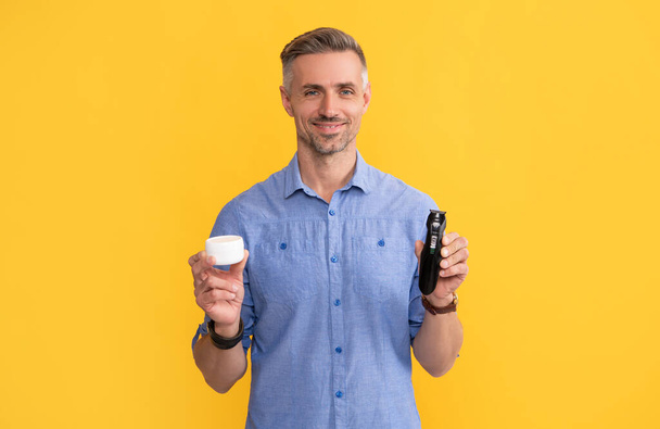 guy showing electriv shaver and cream on yellow background, personal care - Foto, Bild