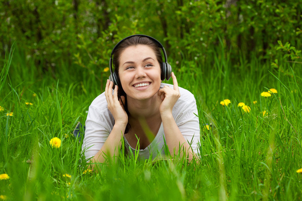 Mujer riendo con auriculares en la hierba
 - Foto, Imagen