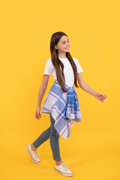 hipster cheerful child in casual clothes full length walk on yellow background - Photo, Image