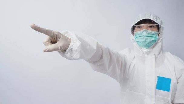 Arzt im PSA-Anzug mit weißen medizinischen Gummihandschuhen und klarer Brille und grüner N95-Gesichtsmaske zum Schutz vor Coronavirus-Pandemie. Geste Handzeichen setzen. Stellvertretender Sieg über das Virus. Isoliert. - Foto, Bild