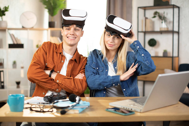 Young couple using VR headset and laptop for playing games - Фото, изображение