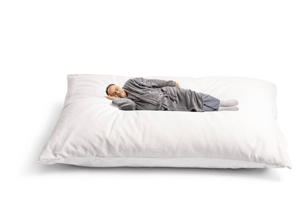 Mature man in a bathrobe sleeping on a giant pillow isolated on white background - Foto, immagini