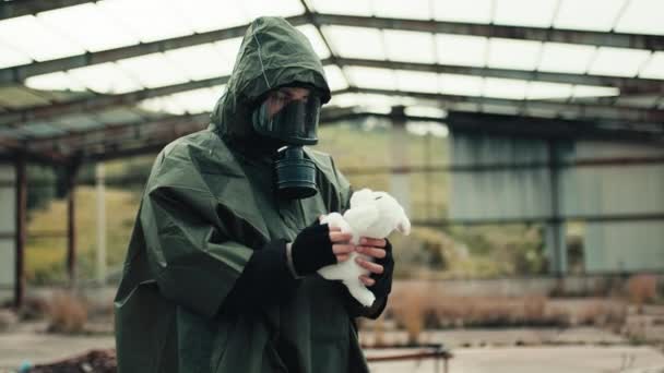 Een man met een gasmasker vindt een opgevuld dier in een door oorlog verscheurd ziekenhuis. - Video