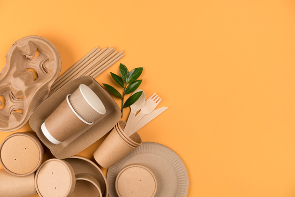 Utensilios de comida de papel Kraft, recipientes de papel y tazas, bebiendo pajitas sobre fondo naranja con espacio para copiar. Concepto de embalaje de papel de comida callejera. Vista superior - Foto, imagen
