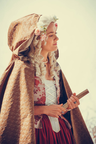 Portrait of blonde woman dressed in historical Baroque clothes with old fashion hairstyle, outdoors. Luxurious medieval dress - 写真・画像