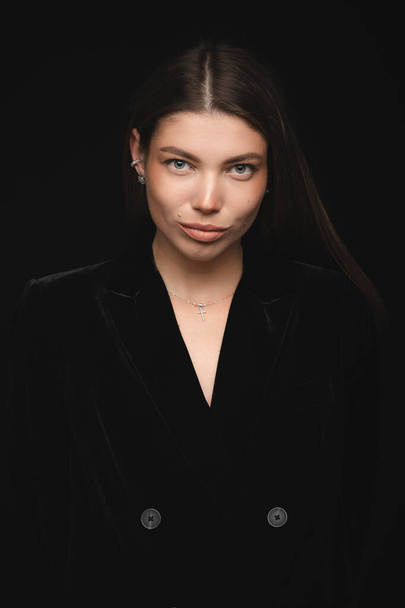 Fashionable studio portrait of a beautiful young girl in black hat on a black background. Low key. - Fotografie, Obrázek
