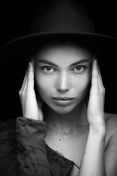 Retrato de estudio de moda de una hermosa joven con sombrero negro sobre un fondo negro. Tecla baja. - Foto, imagen
