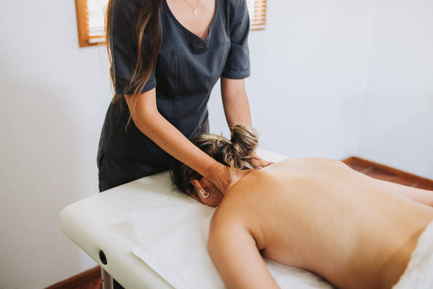 Terapeuta latina fazendo uma massagem nas costas e pescoço para uma paciente feminina de face para baixo. Wellness center spa. Cuidados da pele. - Foto, Imagem
