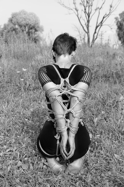 Gebonden vrouw knielen. Zwart-wit foto, Shibari. - Foto, afbeelding