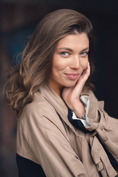 Attractive white caucasian girl in a stylish raincoat on a city street - Photo, image