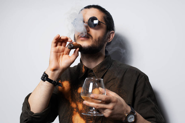 Studio portrait of young man with a cigar and whiskey on white background. - Fotoğraf, Görsel