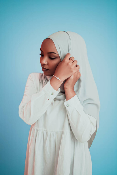Portrait of young modern muslim afro beauty wearing traditional islamic clothes on blue background. Selective focus  - Foto, imagen