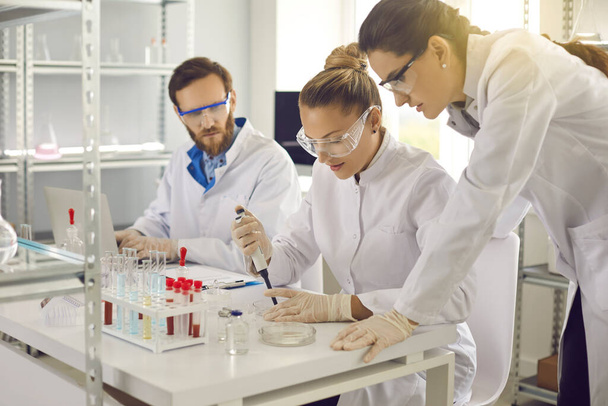 Group of scientists conducting an experiment in a pharma or biotech science laboratory - Photo, image