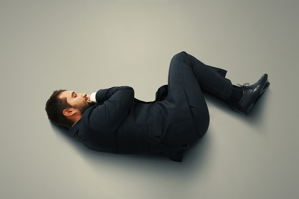 man sleeping on the grey floor - Фото, изображение