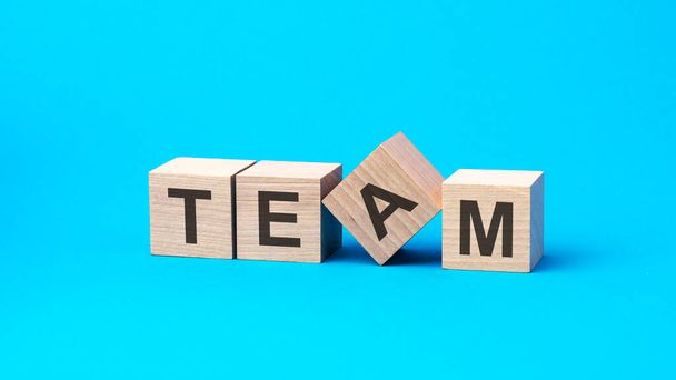 team - word is written on wooden cubes close-up. bright blue background, financial business concept, blue background. team - short for together everyone achieves more - Photo, Image