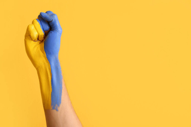 Man with clenched fist painted in colors of Ukrainian flag on yellow background - Fotó, kép