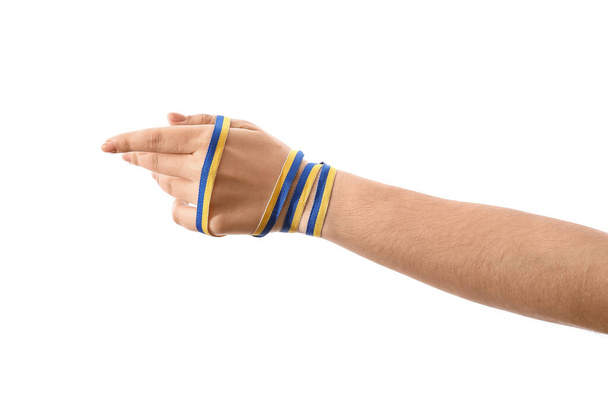 Female hand with ribbon in colors of Ukrainian flag on white background - 写真・画像