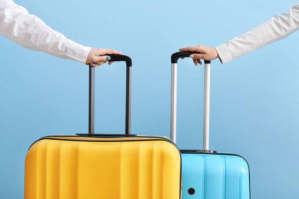 Female hands with suitcases in colors of Ukrainian flag on blue background - 写真・画像