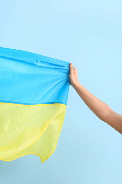 Female hand with national flag of Ukraine on color background - Photo, Image