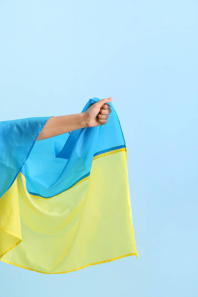 Женская рука с национальным флагом Украины на цветном фоне - Фото, изображение