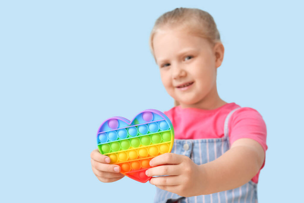 Little girl holding heart shaped pop it fidget toy on color background - 写真・画像